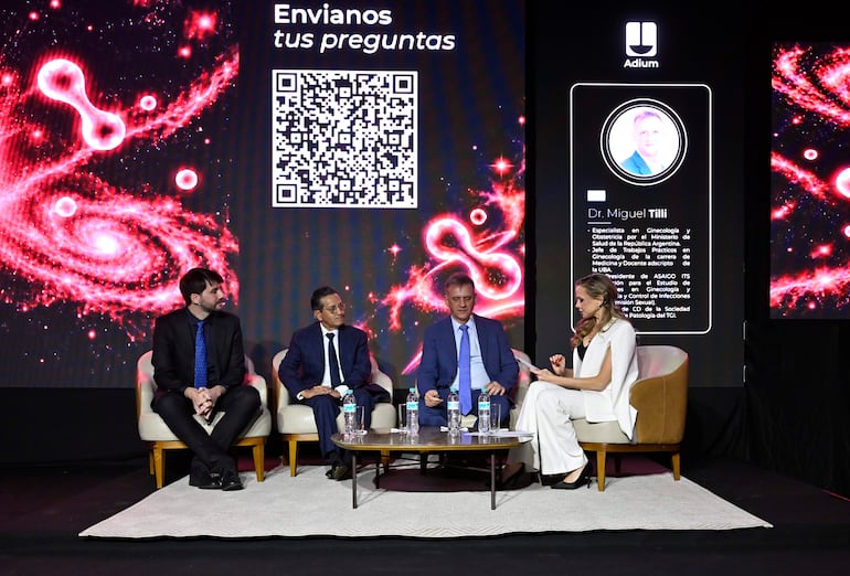 Carolina Sosky, con blusa blanca, habla en un panel, mientras tres hombres la escuchan: uno en traje negro, otro en azul oscuro y un canoso en celeste.