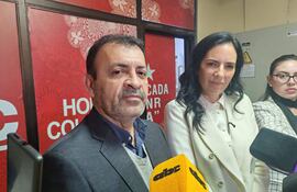 Miguel Ángel del Puerto en traje oscuro, Claudia Centurión con chaqueta blanca, en conferencia con micrófonos de prensa.