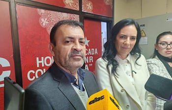 Miguel Ángel del Puerto en traje oscuro, Claudia Centurión con chaqueta blanca, en conferencia con micrófonos de prensa.