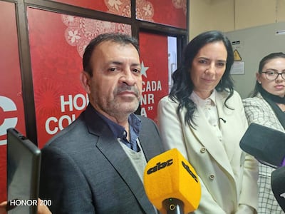 Miguel Ángel del Puerto en traje oscuro, Claudia Centurión con chaqueta blanca, en conferencia con micrófonos de prensa.