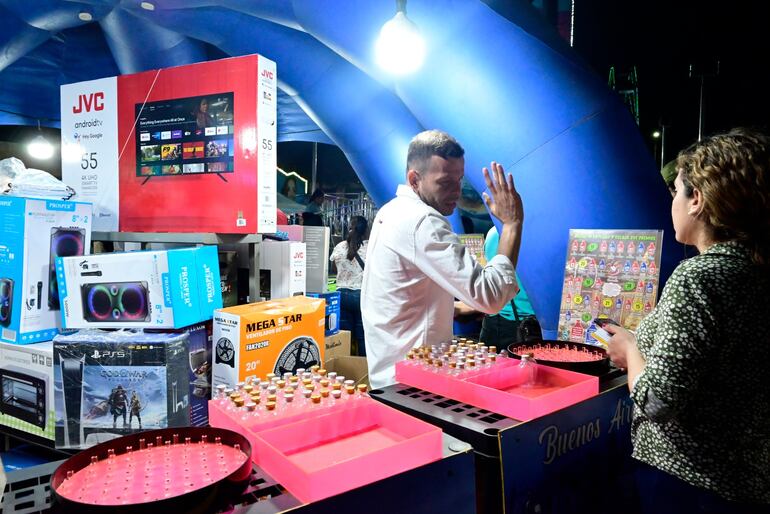 Un empleado explica las reglas del juego con argollas y un pote enumerado al equipo periodístico de ABC. La sumatoria de los números en donde caían los anillos representaba una cantidad de pequeñas botellitas. Los afectados apuntaron a trampas en las sumas hechas por los empleados, que les impedía ganar.