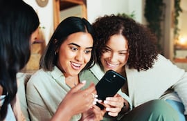 Amigas ven algo en redes sociales en el smartphone.