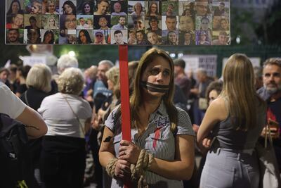 Una persona sostiene un cartel con fotografías de rehenes y víctimas israelíes mientras la gente conmemora un mes desde el ataque de Hamás contra Israel el 7 de octubre durante una manifestación conmemorativa frente a la Knesset (parlamento) israelí en Jerusalén.