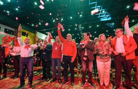 Lilian Samaniego sonríe entre un grupo de personas con ropa roja, todos celebrando con pañuelos en un ambiente festivo.