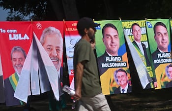 AME1288. BRASILIA (BRASIL), 30/09/2026.- Un hombre camina frente a una tienda informal de banderas con la imagen del presidente de Brasil y candidato a la reelección, Luiz Inácio Lula da Silva y del candidato presidencial, Flávio Bolsonaro, este lunes en Brasilia (Brasil). Mientras las encuestas hablan de una extrema igualdad entre el presidente progresista Luiz Inácio Lula da Silva y el ultraderechista Flávio Bolsonaro, analistas consideran que el resultado de las elecciones brasileñas del 4 de octubre depende de un amplio sector que observa el proceso con distancia y escepticismo: los indecisos. EFE/Andre Borges