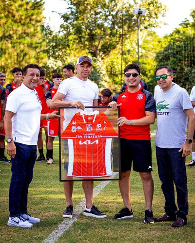 Gustavo Arévalos recibe la camiseta encuadrada de General Caballero de Juan León Mallorquín. Lo acompañan el presidente Julio César Aldama (izq.), el gerente deportivo Julio Sebastián Aldama y el vicepresidente Óscar Gavilán Dávalos. El emotivo momento se vivió en las instalaciones de Puma Resort.