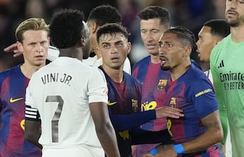 El delantero brasileño del Barcelona Raphinha (d) discute con su compatriota del Real Madrid Vinicius Junior (2i) durante el encuentro correspondiente a la jornada 35 de LaLiga que FC Barcelona y Real Madrid disputan este domingo en el Camp Nou, en Barcelona. EFE/Enric Fontcuberta