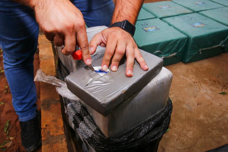 Un agente de la Secretaría Nacional Antidrogas (Senad) realiza la toma de muestra de uno de los paquetes para llevar a cabo el análisis de la sustancia.