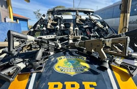 Automóvil de la Policía Rodoviaria Federal con rifles organizados sobre el capó en un espacio exterior.
