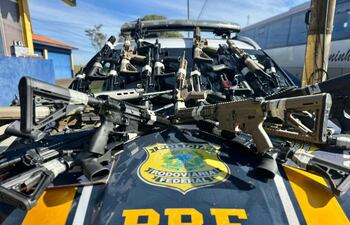Automóvil de la Policía Rodoviaria Federal con rifles organizados sobre el capó en un espacio exterior.