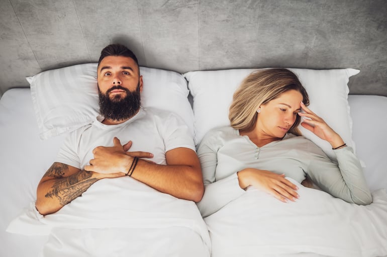Pareja cansada en la cama, imagen ilustrativa.