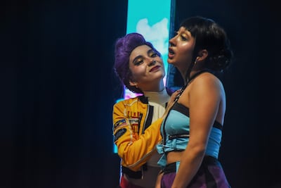 Mujer con cabello morado y chaqueta amarilla habla, mientras otra de cabello oscuro y blusa azul responde con intensidad.