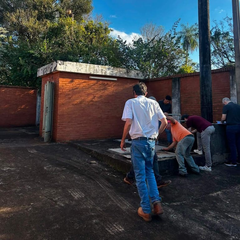 Seis hombres realizando tareas de verificación en una estación de bombeo, algunos agachados y otros de pie en un entorno de construcción.