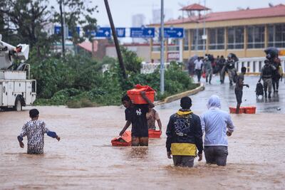 Personas cruzan una avenida inundada por el paso del huracán 'John' en la parte alta del puerto de Acapulco, en Guerrero (México).