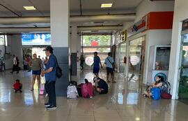 Pasajeros de la Estación de Buses de Asunción aguardan la salida de colectivos parados o sentados en el suelo.