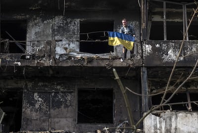 Un hombre iza una bandera nacional ucraniana en el lugar donde un misil ruso impactó contra un edificio residencial en Kiev, Ucrania, el 14 de octubre de 2026, en medio de la actual invasión rusa.