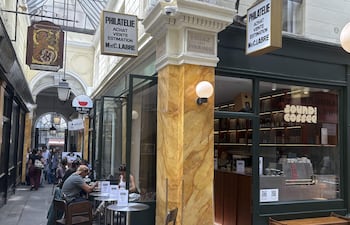 Cafetería de especialidad en el pasaje de los Panoramas, en el local de una antigua tienda de compraventa de sellos. Platos argentinos, chinos, indios, italianos, japoneses... viajar por todo el mundo es posible sin salir del pasaje cubierto de los Panoramas, el más antiguo de París, donde las 'trattorías' y los 'bistrós' alternan con antiguos locales de filatelia, dedicados al coleccionismo y la compraventa de sellos. La sucesión de carteles resulta en una cacofonía visual, donde las anacrónicas ofertas de '70 sellos a granel' comparten espacio con los 'cafés de especialidad' y los 'matcha latte de fresa y chocolate'.