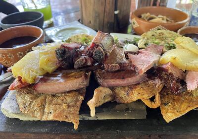 ACOMPAÑA CRÓNICA: MÉXICO GASTRONOMÍA***MEX9470. VALLADOLID (MÉXICO), 25/07/2022.- Vista de un platillo preparado con carne ahumada, longaniza y poc chuc servido sobre una tabla el 23 de julio de 2022 en el restaurante Achiote, poblado de Tikuch, Valladolid, estado de Yucatán (México). En la pequeña comunidad de Kaua, en el estado mexicano de Yucatán, 10 restaurantes tradicionales cocinan el poc chuc, un guiso prehispánico a base de carne de puerco, que identifica al lugar al que los guías y visitantes han llamado "La ruta de las tías", parte del camino gastronómico a las ruinas mexicanas de Chichen Itzá. EFE/Lourdes Cruz