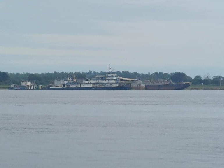 Panorama del río Paraguay con barcazas ancladas, en un día nublado y agua grisácea.