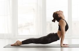 Una mujer hace la postura de la cobra en un mat de yoga