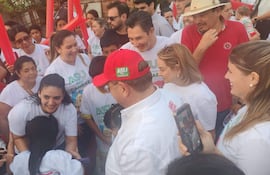 Grupo de personas con camisetas blancas que dicen 'ASU PUEDE CAMBIAR', sonrisas y gestos animados en un ambiente comunitario.