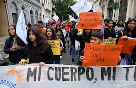 Jóvenes marchan con carteles en la calle, destacando consignas de defensa de derechos, un niño sostiene una pancarta entre ellos.