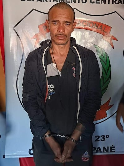 Alcides Rolando Ayala Lovera 'Chino', con expresión seria, esposado, vestido con camiseta oscura, en ambiente policial.