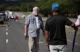 Un hombre sostiene un arma frente a un manifestante en medio de un bloqueo de docentes en la vía Panamericana, en Chame (Panamá).