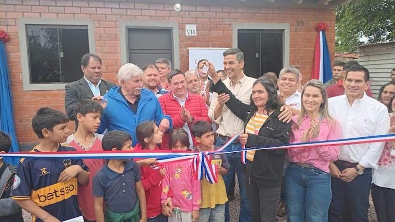 Optaciano Gómez Verlangieri de abrigo azul y Manuel Aguilar en el centro, rodeados de personas aplaudiendo en un ambiente de celebración.