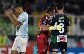 El delantero del Gremio, Carlos Vinícius (izq.), reacciona tras fallar un penal ante el portero de Palestino, Sebastián Pérez (centro), y el defensa Enzo Roco (der.), durante el partido de fútbol de la fase de grupos de la Copa Sudamericana entre el Palestino de Chile y el Gremio de Brasil, en el estadio Municipal de La Cisterna en Santiago.