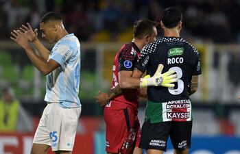 El delantero del Gremio, Carlos Vinícius (izq.), reacciona tras fallar un penal ante el portero de Palestino, Sebastián Pérez (centro), y el defensa Enzo Roco (der.), durante el partido de fútbol de la fase de grupos de la Copa Sudamericana entre el Palestino de Chile y el Gremio de Brasil, en el estadio Municipal de La Cisterna en Santiago.