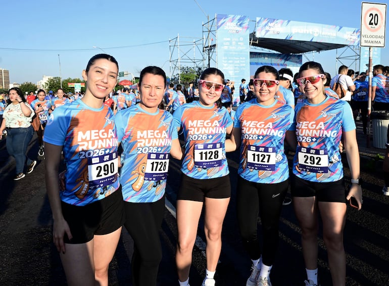 Cinco mujeres en camisetas deportivas 'MEGA RUNNING 2026', sonriendo y en diversas posturas, corren al aire libre.