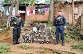 Dos policías nacionales en uniformes tácticos observan máquinas desmanteladas en un entorno residencial rústico.