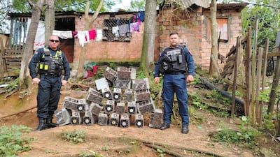 Dos policías nacionales en uniformes tácticos observan máquinas desmanteladas en un entorno residencial rústico.