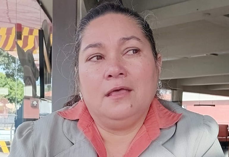 Clementina Ruiz Díaz Ojeda en traje gris y blusa naranja, sentada en un café con expresión seria y ambiente cálido.