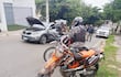 Policía Nacional en uniforme negro y chaleco, junto a SUV gris con capó abierto en calle con vegetación.