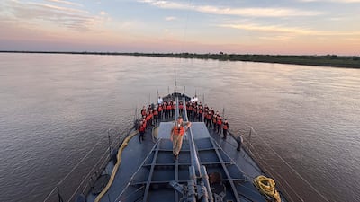 Grupo de hombres sonrientes con chalecos salvavidas en el Buque Escuela Cañonero Paraguay, al atardecer en un ambiente acuático.