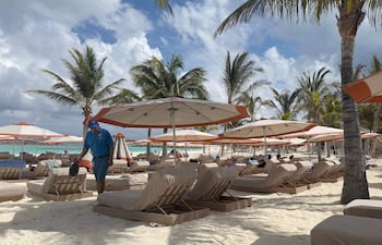 Fotografía cedida por Norwegian Cruise Line (NCL) de un trabajador limpiando en una playa en Great Stirrup Cay, la isla privada de la compañía en Bahamas.