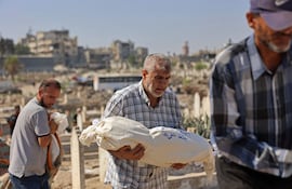Un hombre lleva en brazos el cadáver de un familiar fallecido en un ataque israelí conta un edificio en la Ciudad de Gaza.