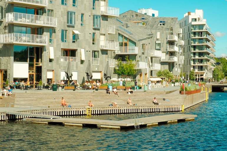 Personas tomando el sol y nadando en la piscina de agua de mar de Sørenga en el puerto de Oslo durante un soleado día de verano.