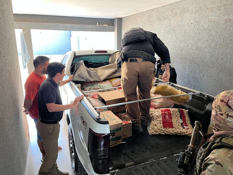 Agentes especiales de la Senad retiran los víveres debajo de los cuales estaban los fusiles, en la carrocería de una camioneta.