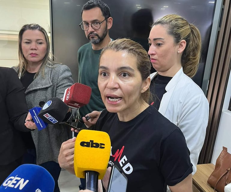 Rossana González con camiseta negra habla intensamente, mientras dos mujeres y un hombre la escuchan, todos sosteniendo micrófonos.