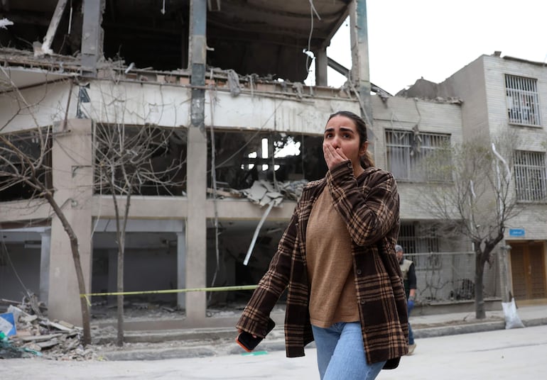 Una mujer reacciona ante el daño a un edificio en Teherán, donde Estados Unidos e Israel mantienen el conflicto bélico con Irán. EFE/EPA/ABEDIN TAHERKENAREH.