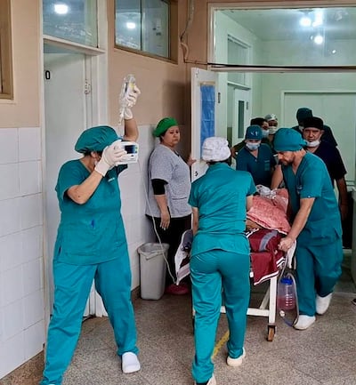 Seis médicos en uniformes quirúrgicos verdes, activo en el pasillo del hospital, asisten a un paciente en camilla.