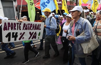 Personas sostienen carteles y banderas durante una manifestación este martes, en Asunción (Paraguay).