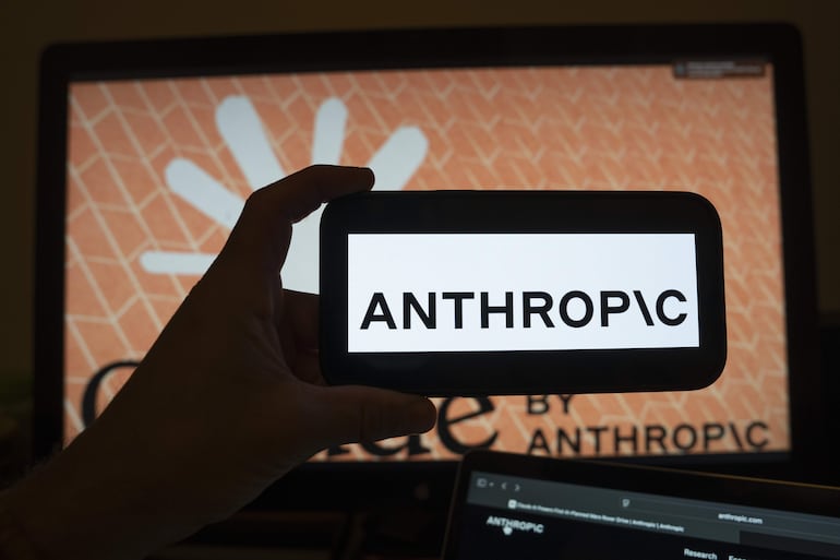 Una persona sostendiendo un teléfono con el logotipo de la inteligencia artificial (IA) Anthropic.