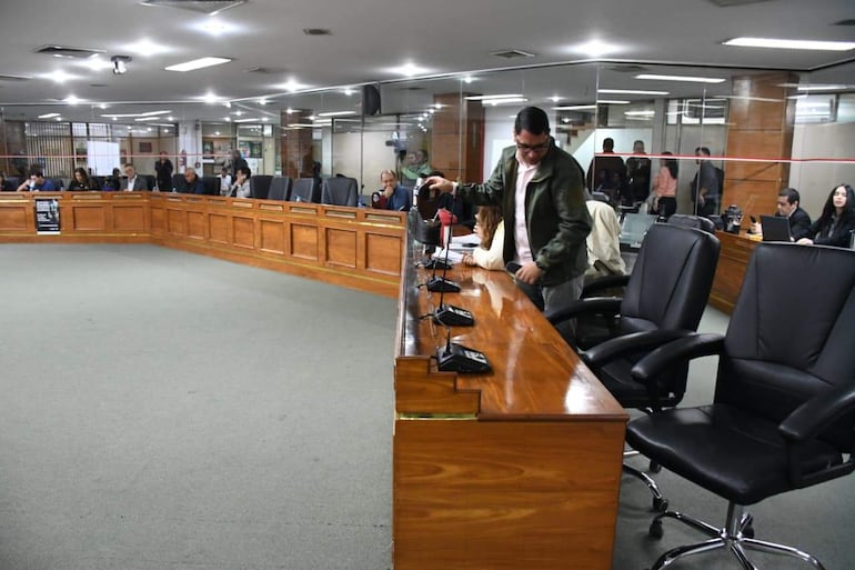 Marcelo Centurión con chaqueta verde ajusta un micrófono mientras Felix Ayala observa, en sala de reuniones iluminada y sencilla.