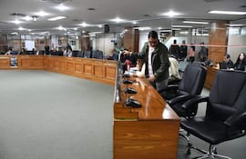 Marcelo Centurión con chaqueta verde ajusta un micrófono mientras Felix Ayala observa, en sala de reuniones iluminada y sencilla.