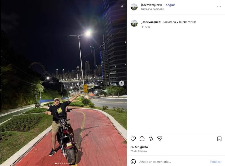 Joven con gorra y ropa casual sobre motocicleta, posando en una calle iluminada de Balneario Camboriú.