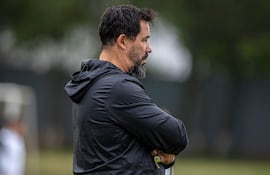 Pablo Sánchez Vitamina con chaqueta negra, sosteniendo un silbato, rodeado de jugadores en un campo de entrenamiento.